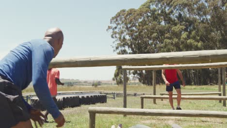 Diverse-fit-group-going-under-and-over-hurdles-on-obstacle-course-in-the-sun