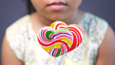 child holding colorful heart-shaped lollipops