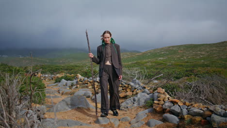 trekking girl holding stick hiking on mountains trail. tourist walk scenic path