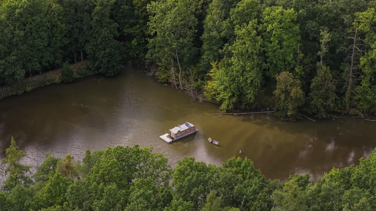 Houseboat on a pond surrounded by nature and trees, captured from a drone, evoking solitude and tranquility