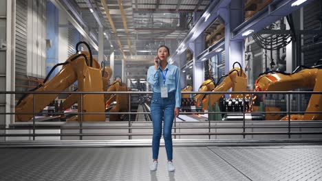 full body of asian female with industrial robotic arms working, she is speaking with someone in the phone