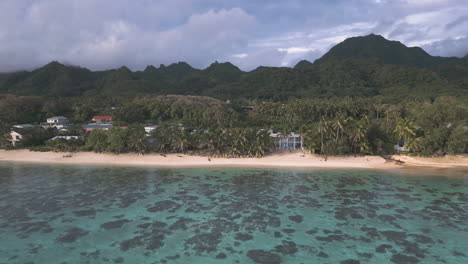 aerial tracking left passes hotels along rarotonga cook islands mountains overlooking sandy beach coastline homes