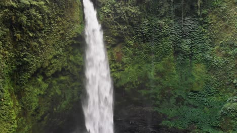 a drone slowly tilts down to reveal the magnificent nungnung waterfall in bali, indonesia