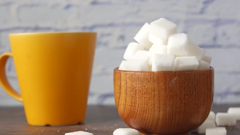 sugar cubes in wooden bowl with yellow mug