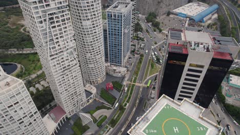 Aerial-view-above-some-skyscrapers-with-helicopter-landing-zone-in-Mexico-City,-with-busy-streets