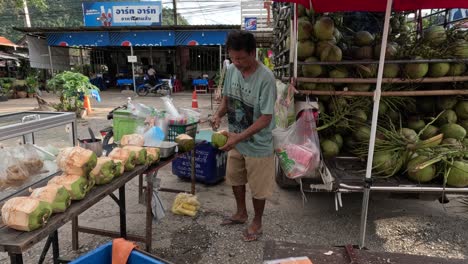 man organizing coconuts at a street market.