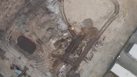 top down aerial of excavators collecting rubble from demolished building on construction site