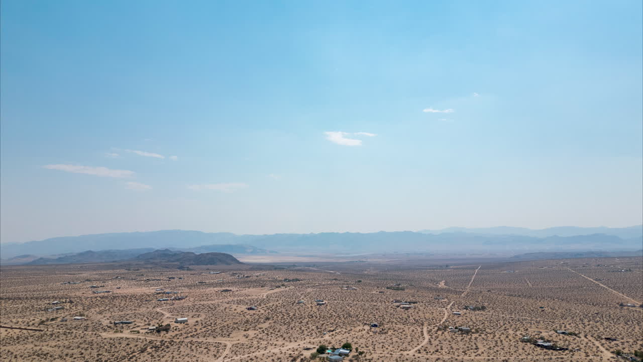 조슈아 트리 (joshua tree) 의 드론 하이퍼스 (drone hyperlapse) 사막 풍경 정오에 구름이 쌓인 하늘과 근처의 불에서 나오는 연기가 있습니다.