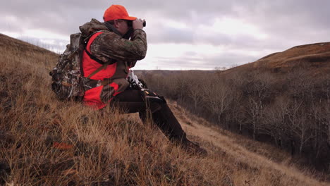 hunter sitting on the hillside scouting the terrain for his prey