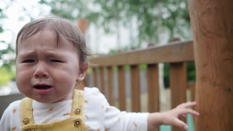 Caucasian-little-baby-girl-crying-and-screaming-from-pain-at-outside-playground-daytime,-face-close-up-slow-motion