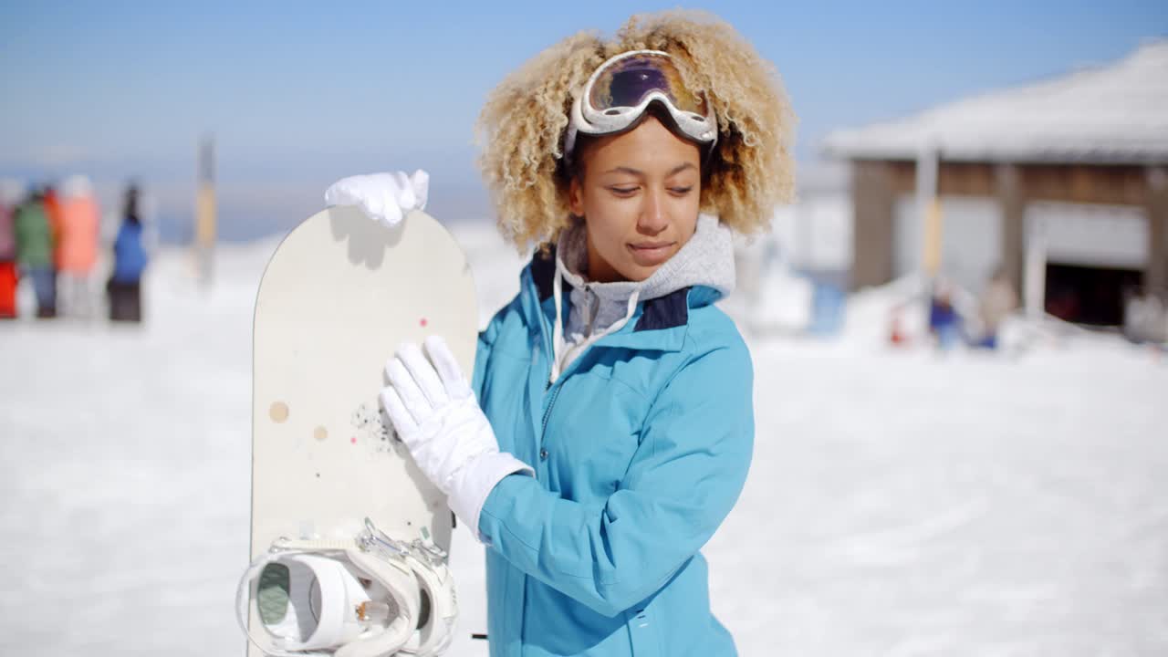 Giovane donna felice e amichevole in posa con uno snowboard