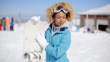 una joven feliz y amigable posando con una tabla de nieve