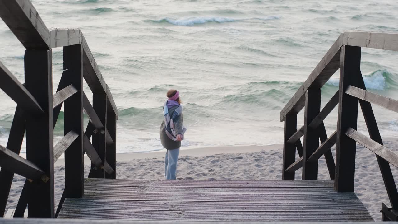 Woman walking down wooden stairs to the beach