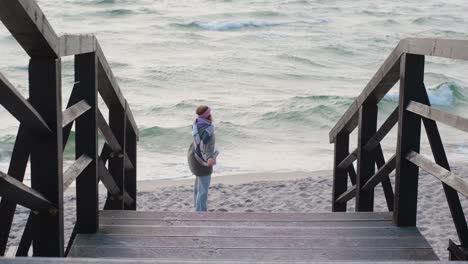 woman walking down wooden stairs to the beach