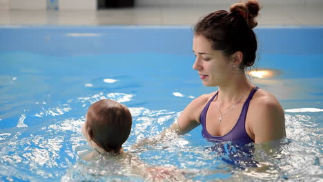 un bebé lindo disfrutando con su madre en la piscina.