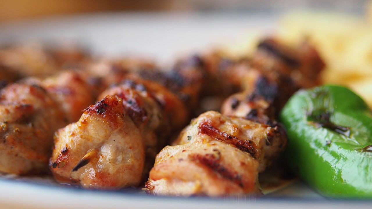 Primo piano di spiedini di pollo alla griglia serviti con verdure e patatine fritte