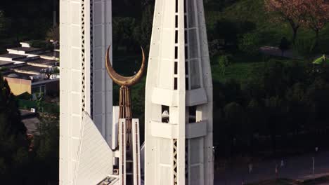 A close-up view focusing on the crescent and two towering minarets of Faisal Mosque in Islamabad, Pakistan.The bronze crescent contrasts beautifully with the white modern design of the minarets