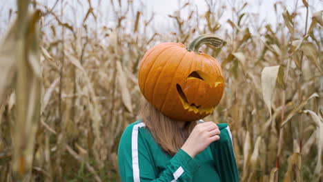 young woman with carved pumpkin head wearing green tracksuit