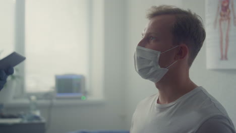 Man-patient-listening-doctor-advices-sitting-in-modern-hospital-office-close-up.