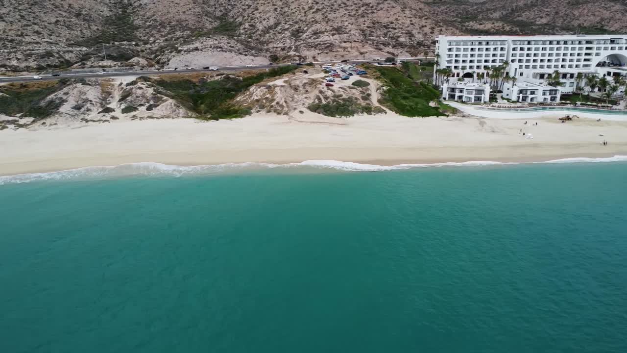 vista aérea de la hermosa costa costera en los cabos con una vista de la playa de arena, una concurrida carretera costera y el mar turquesa y el famoso hotel marquis durante unas vacaciones en méxico