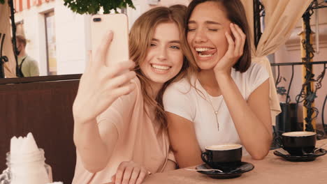 two young women taking a selfie in a cafe