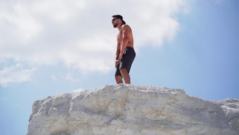 shirtless athlete with strong body resting after heavy training on the sky background. muscular man without shirt on white hill outdoors.