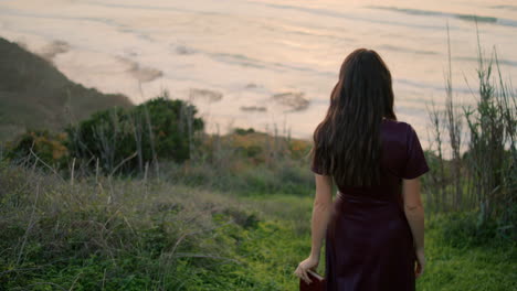 Woman-going-down-shore-holding-book.-Magnetic-girl-walking-cloudy-coast-alone.