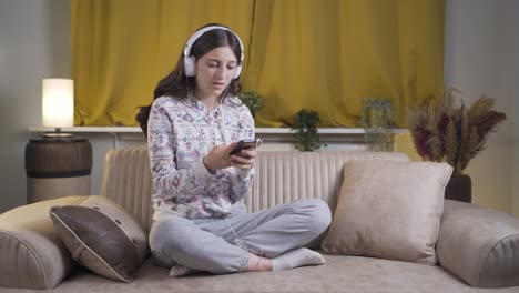 sad and unhappy young woman listening to music at night at home.