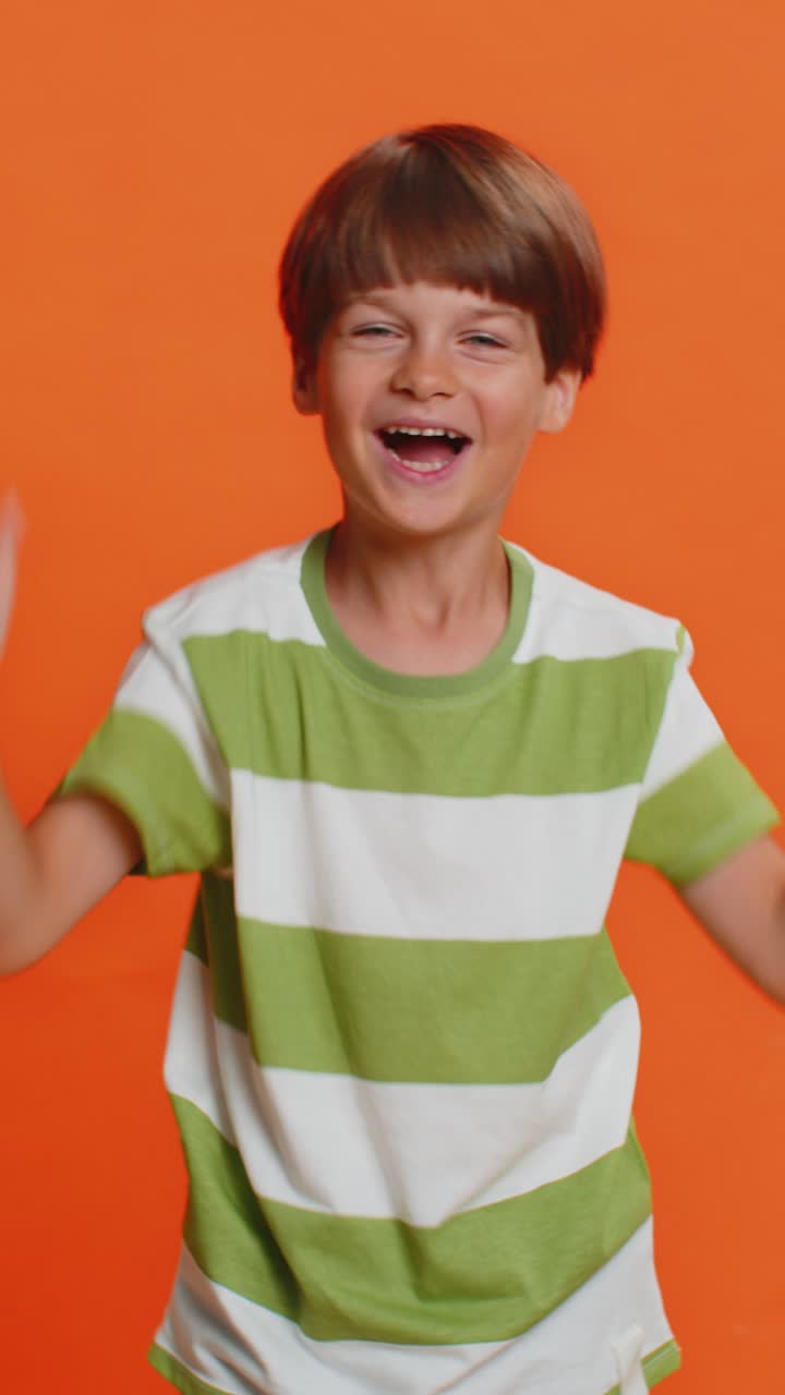 Young cute school boy kid smiling friendly gesturing hello or goodbye welcoming waving hands