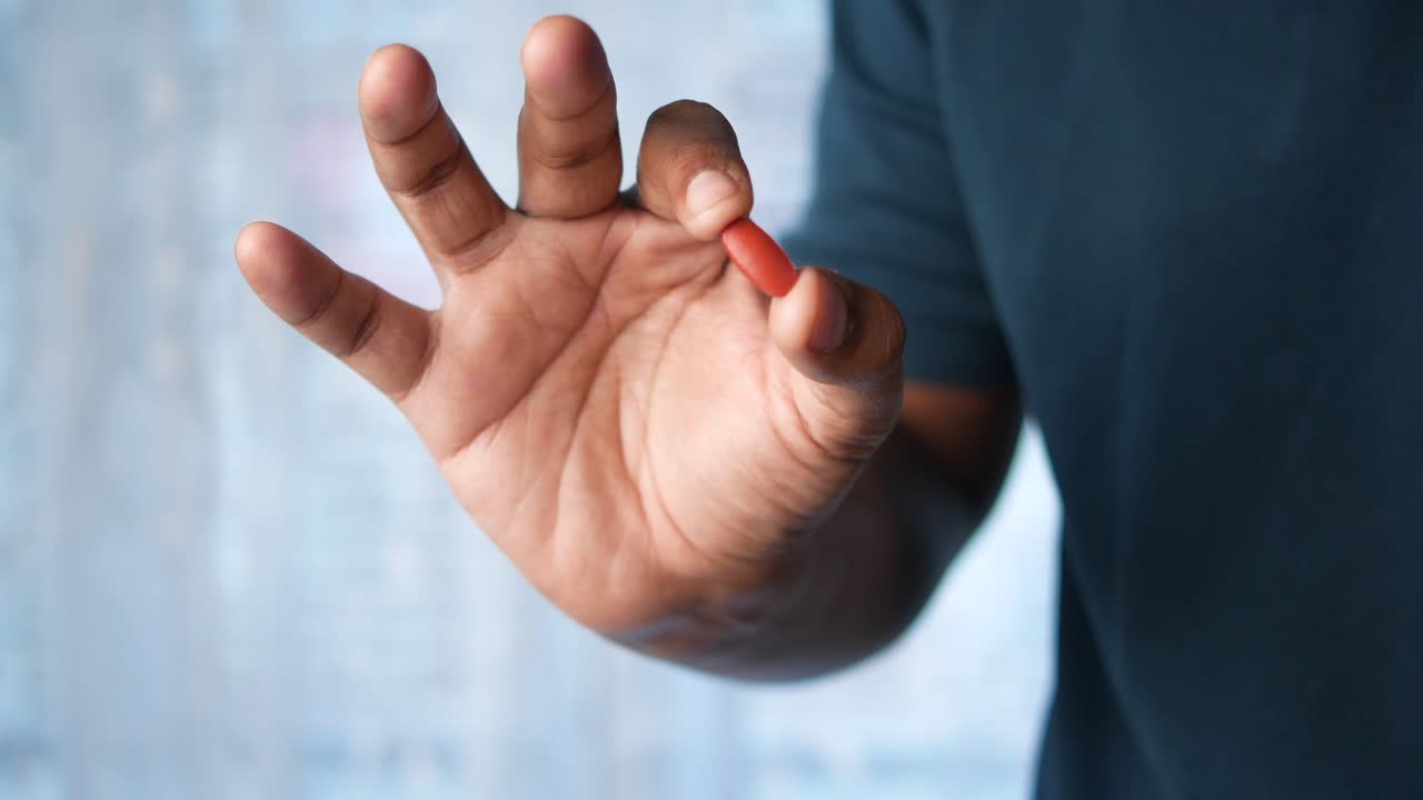 persona que sostiene una píldora roja