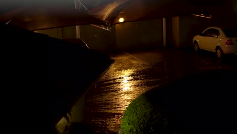 Rainy-night-shot-of-an-eerie-parking-lot-with-shadows-of-car-passing-by