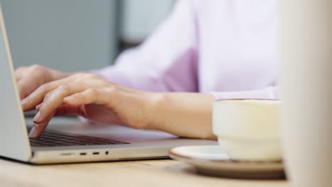 mano de cerca de una mujer de negocios escribiendo teclado computadora portátil en la oficina de escritorio