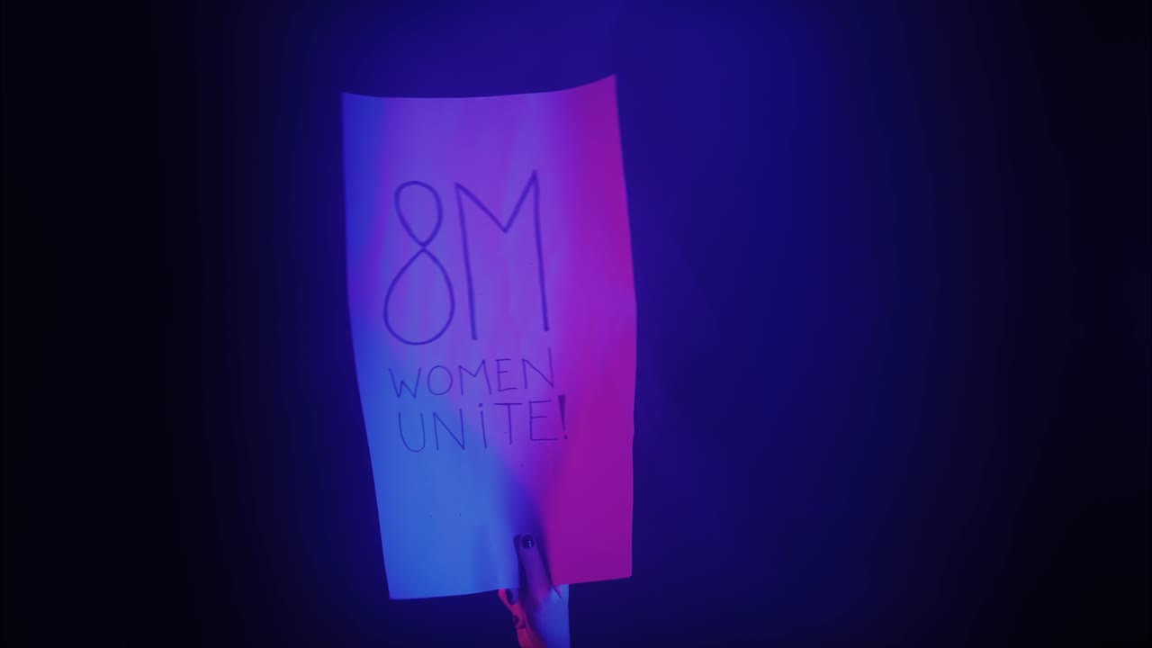 Hand Holding "8M Women Unite!" Protest Sign with Neon Lights