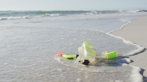 video de una máscara de snorkel de plástico tendida en la arena en la playa