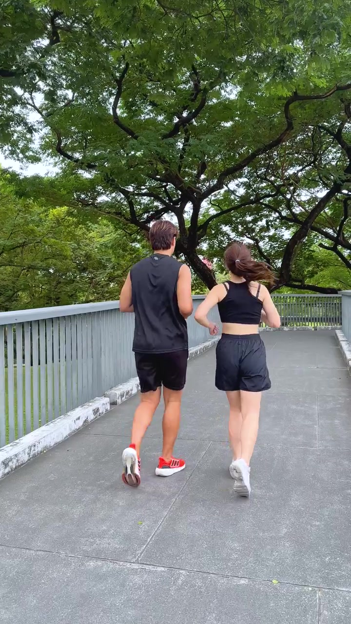 Coppia che fa jogging su un sentiero pavimentato in un parco verde