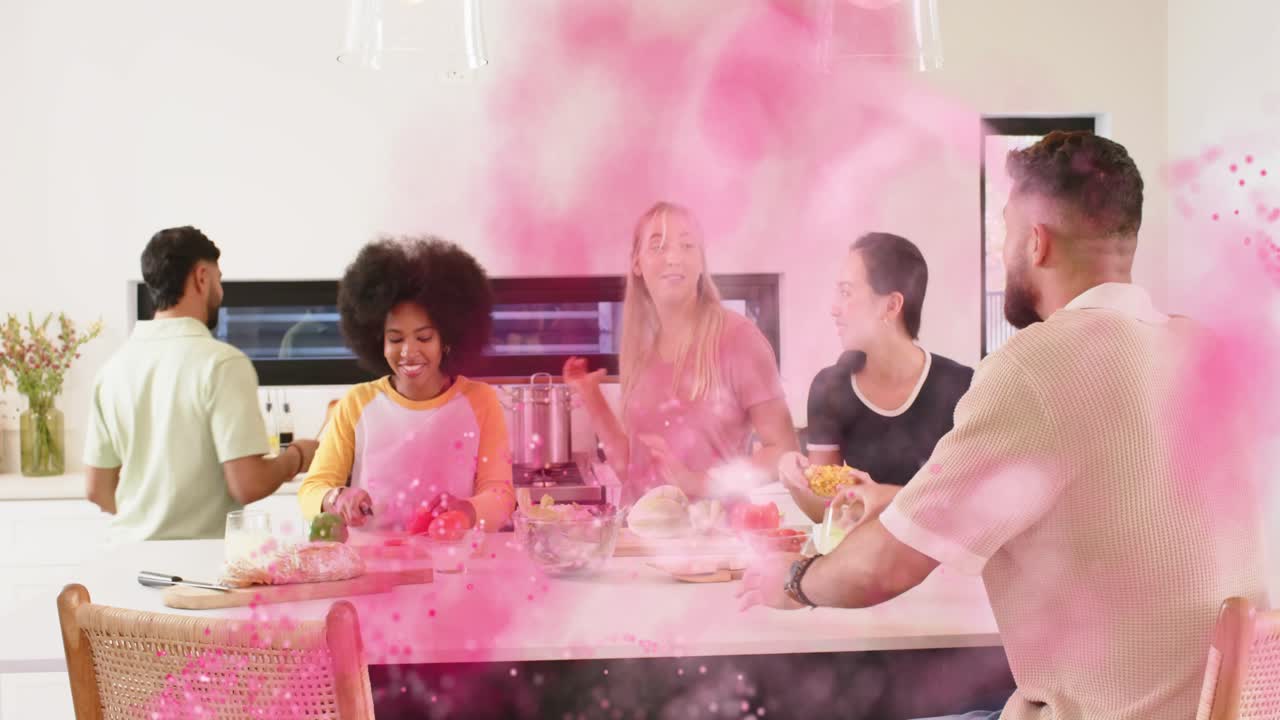Amici che preparano i pasti sull'isola della cucina, tagliano, passano gli ingredienti mentre una sovrapposizione rosa a spirale evidenzia le ciotole