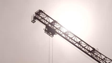 construction tower crane jib and trolley, bright sun in background