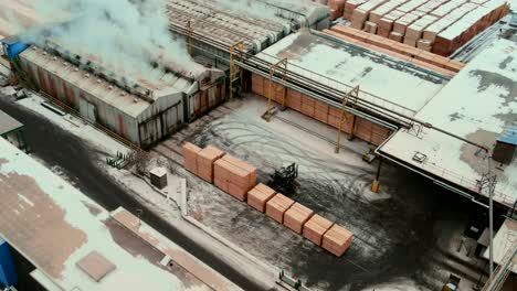 toma aérea de madera contrachapada apilada con montacargas frente a hornos secos industriales para el proceso de eliminación de humedad