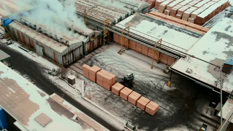 aerial shot of forklift stacking plywood in front of industrial dry kilns for moisture removal process