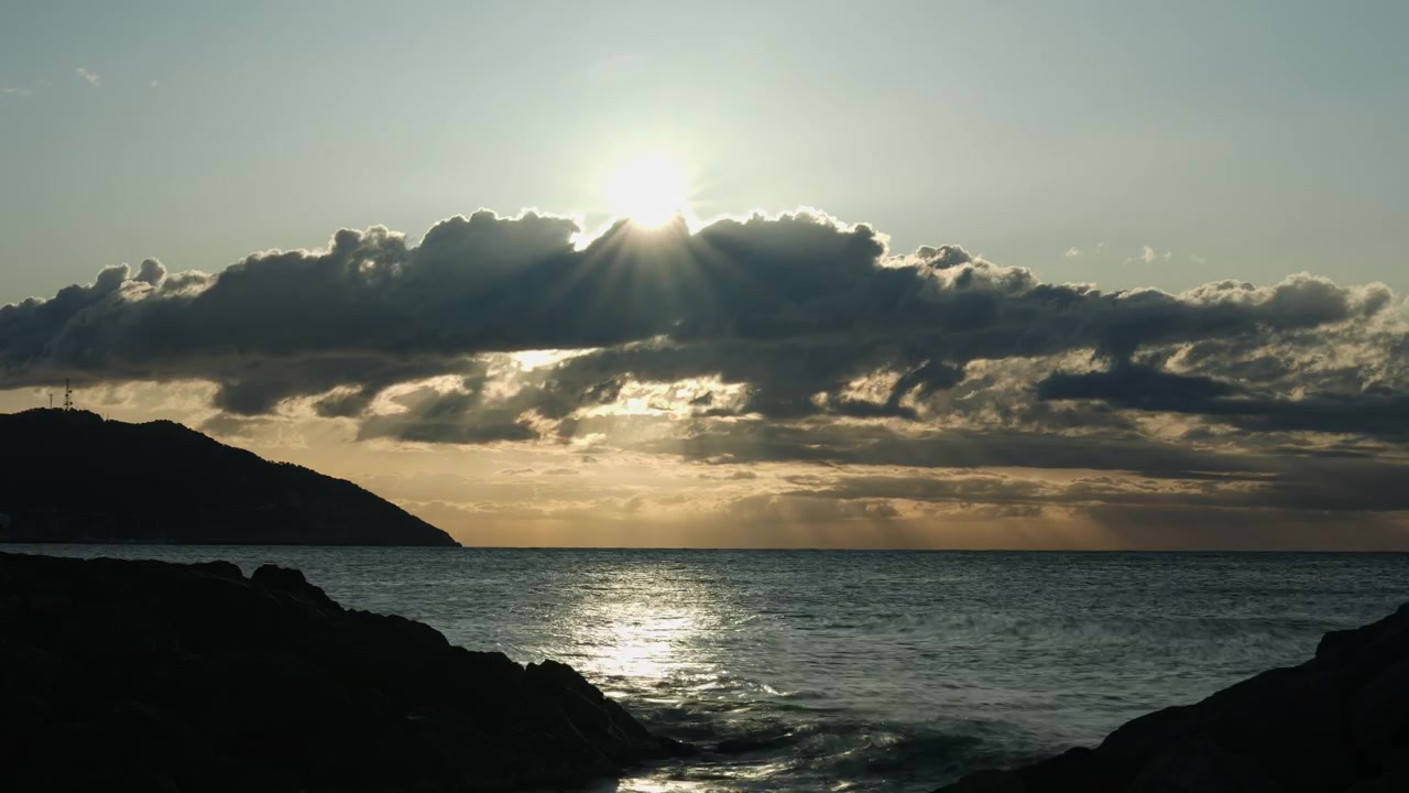 Experience magic of a golden hour time-lapse capturing serene sunrise over a calm sea near a beautiful rocky coastline