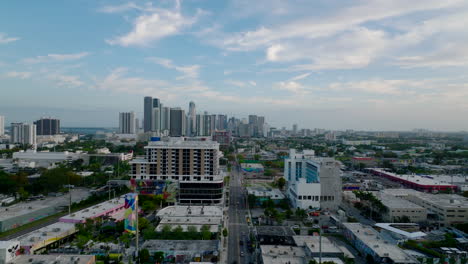 Forwards-fly-above-long-straight-street-in-city.-Group-of-modern-high-rise-apartment-buildings-in-distance.-Miami,-USA