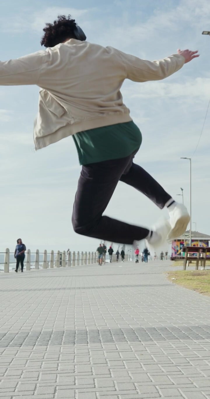 Young Man Dancing and Jumping on Seaside Promenade