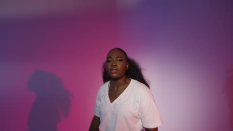 studio shot of young woman dancer dancing against blue and pink lit background 10