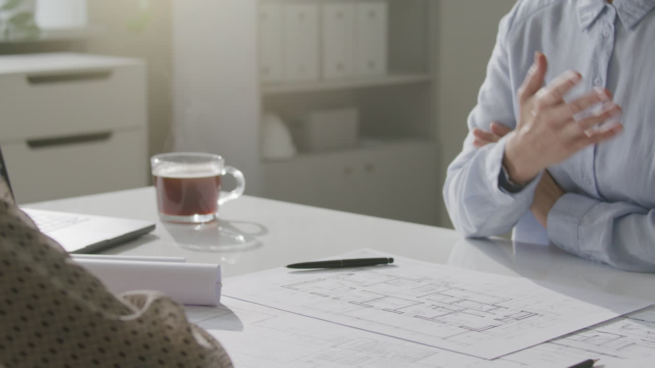 Nærbillede af kvindelige arkitekter, der diskuterer teknisk blueprint ved skrivebordet
