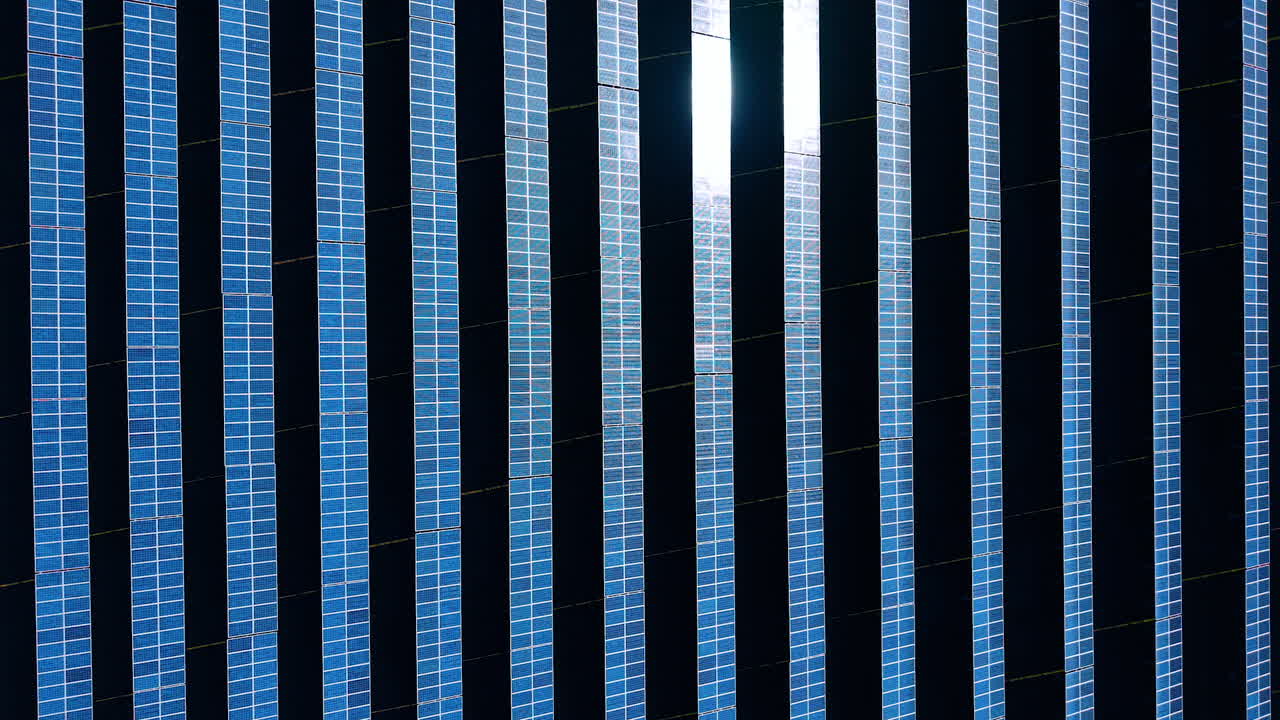 Solar panels create energy on a sunny day in an outdoor field. Rows of solar panels cover the ground, capturing sunlight to generate energy for various uses