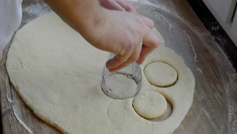 cortar una forma circular de la masa enrollada mientras se preparan productos horneados caseros