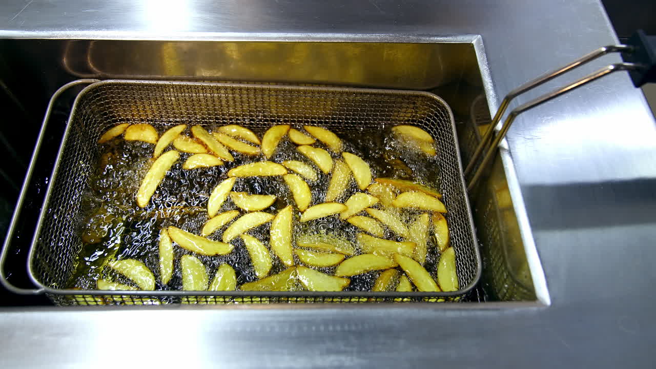 Potato in deep fryer. Crispy fries in the deep fryer in a fast food restaurant. Cooking potato. Junk food concept. Top view. Close up.
