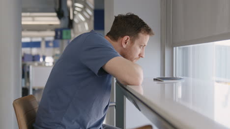 male sitting next to counter in the airport terminal at the gate waiting patiently for the plane to board his flight