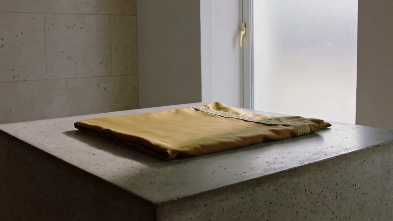 Folded Gold Silk Fabric Resting on a Concrete Pedestal