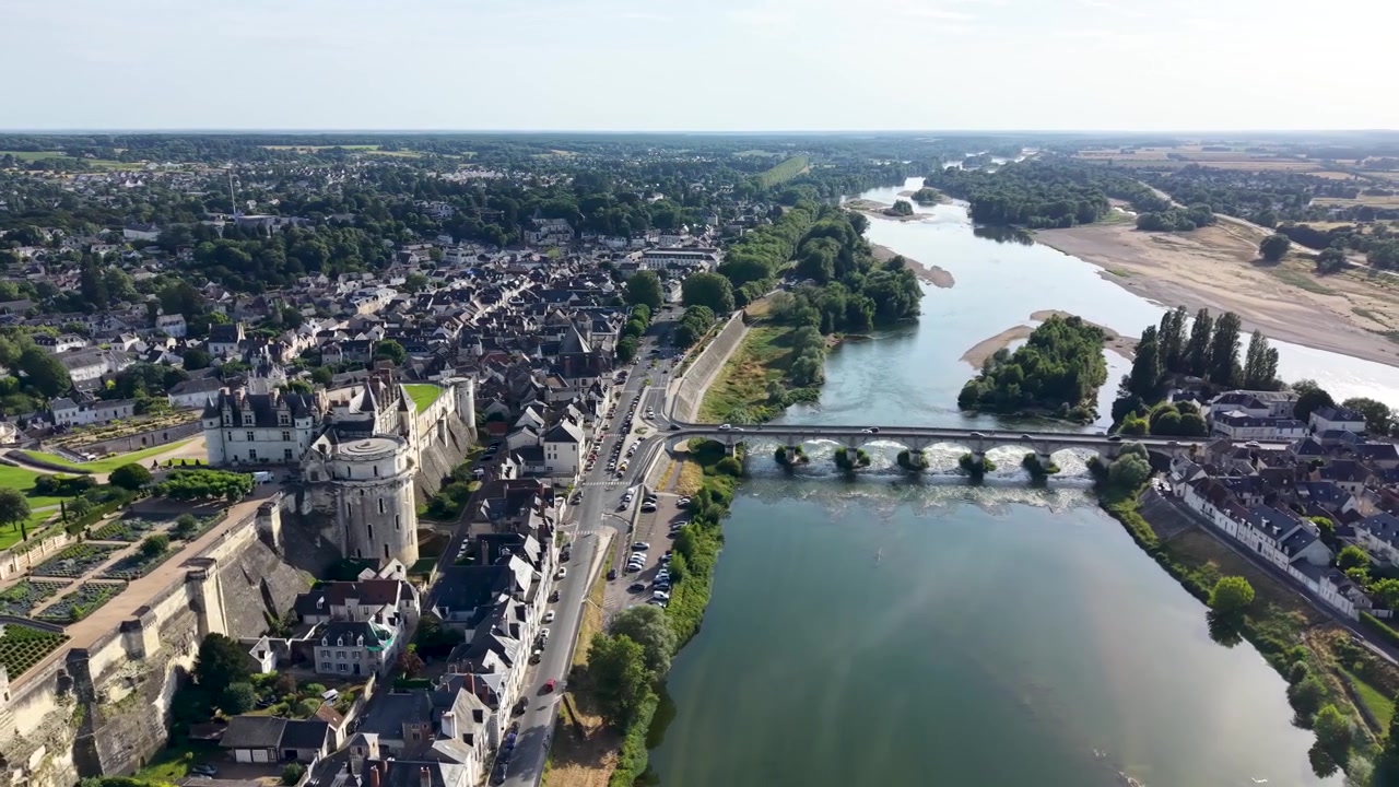 Panorama aéreo cinematográfico amplio con dron del Castillo Real de Amboise con vistas al río Loira, mostrando el histórico castillo real, la Capilla de San Huberto, el puente medieval y el casco antiguo de Amboise